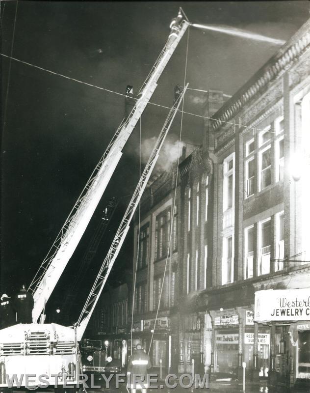 Box 1122-January 8, 1963-Watch Hill's aerial ladder goes to work on the fire in the Barber Memorial Building  roof with Westerly's ladder in the background.