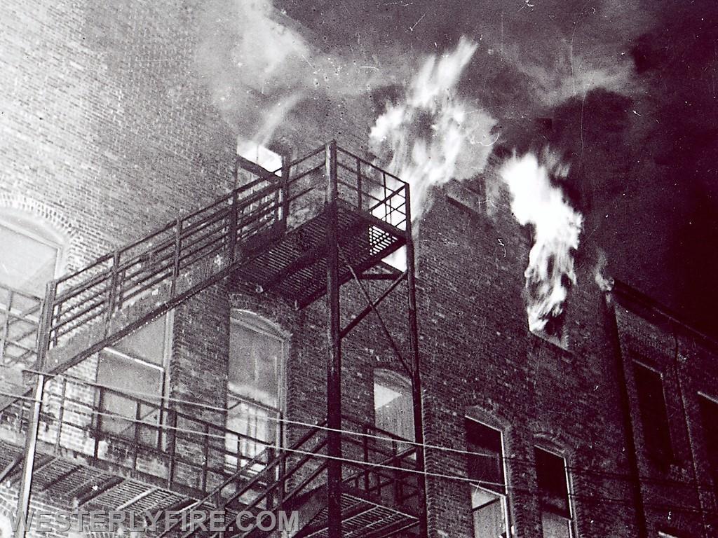 Box 1122-January 8, 1963-A view of the rear of the Barber Memorial Building as fire blows out two windows and the transom above the exit door.