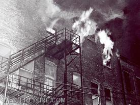 Box 1122-January 8, 1963-A view of the rear of the Barber Memorial Building as fire blows out two windows and the transom above the exit door.