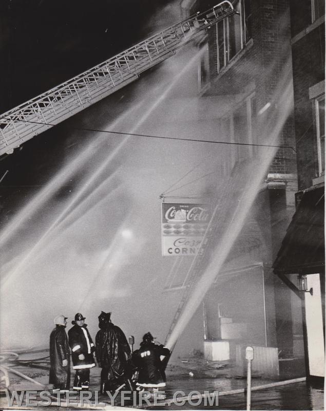 Box 3111-March 14, 1975-Firefighters pour water into the front of the Potter-Langworthy Building. Westerly Ladder 1 protecting the Wayfarer.
