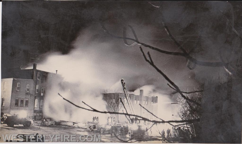 Box 3111-March 14, 1975-Westerly, Watch Hill, Pawcatuck and Wequetequock firefighters pour water into the rear of the Potter-Langworthy Building.

