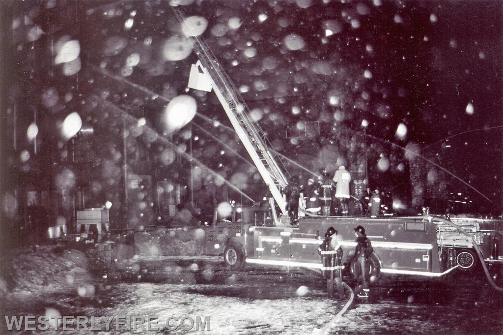 Box 3111-March 14, 1975-Snow and smoke obscure the firefighters working in the rear. Watch Hill's ladder truck is providing an elevated stream.