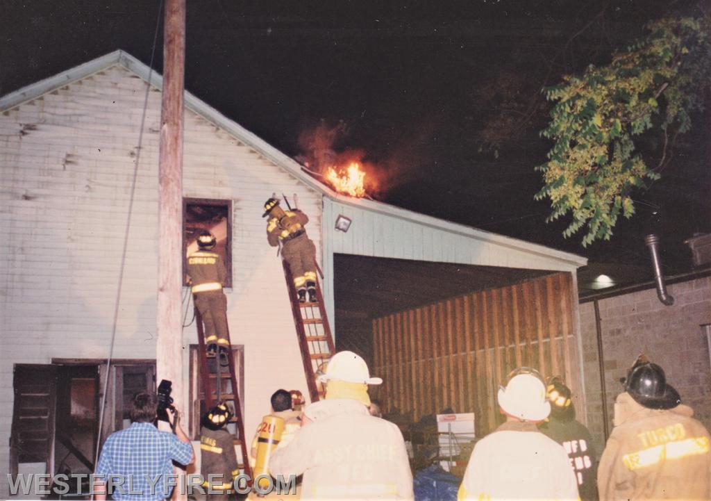 Box 1123-7-17-1994-117 Main St.-Firefighters work via ground ladders on the C-side as fire erupts from the roof