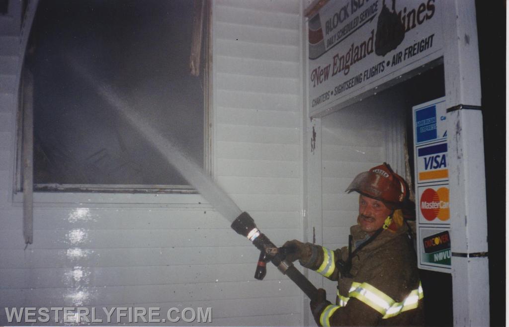 Box 1328-8-9-1998-Westerly Airport-Ladder Co. Foreman Eric Fallon operates an 1 3/4 inch hose line through a window. 