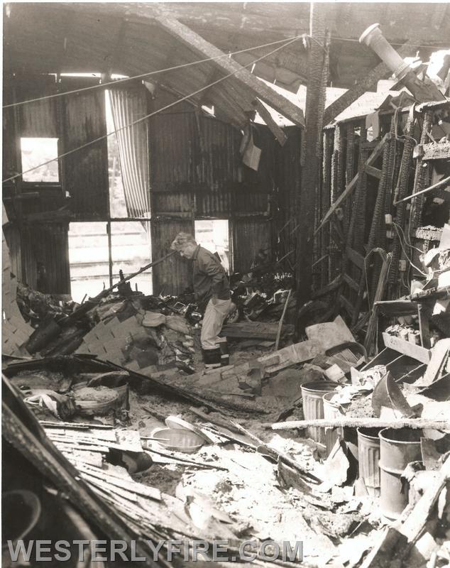 Box 3124-9-14-1975-Fire Chief Robert Mackay inspects the damage to the Westerly Grain building. Note extensive fire damage and partial collapse of the roof members.