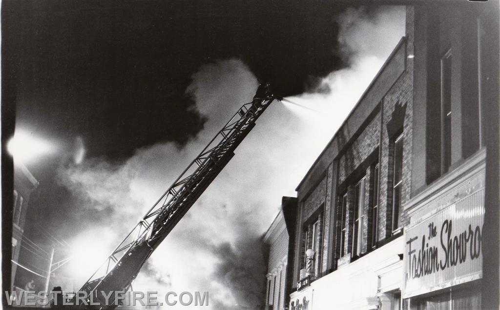 Box 534-March 26, 1978-Pawcatuck's ladder truck using its ladder pipe to protect the D side exposure at the Chase Fire on High St. Note the heavy smoke banking down.